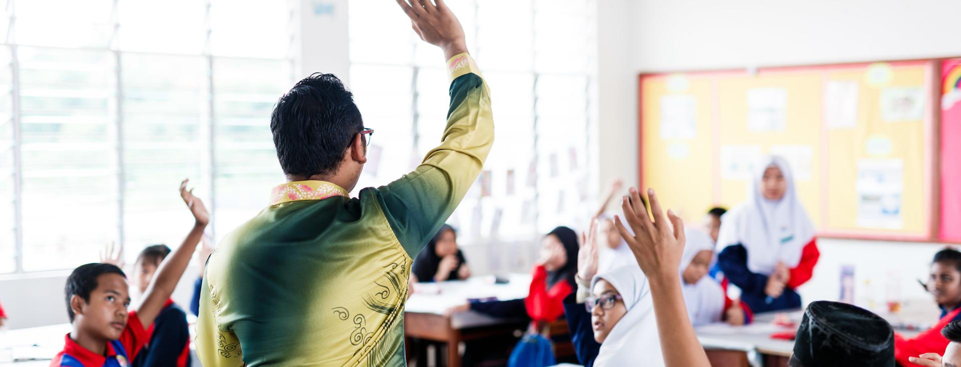 teacher asking students a question with raised hands
